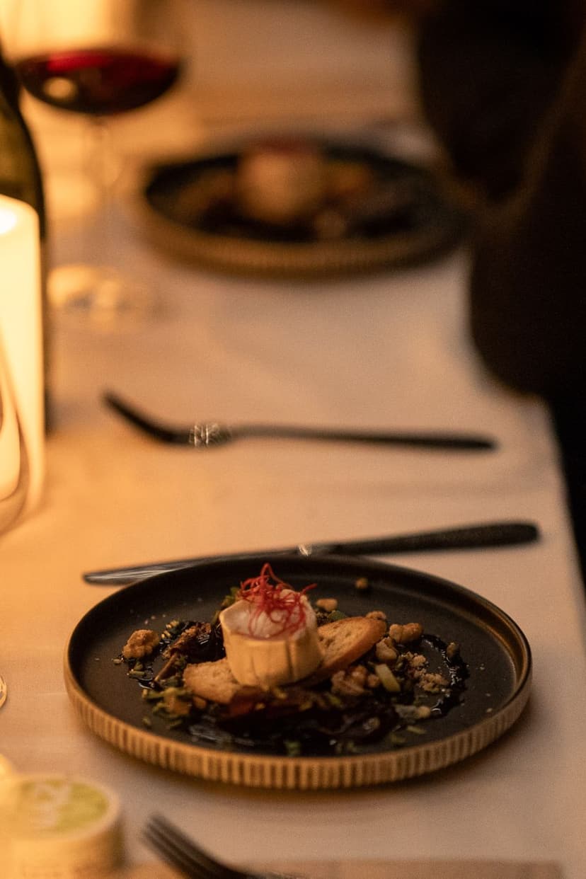 Uppdukat bord i levande ljus med en förrätt, vinglas och en flaska vitt vin