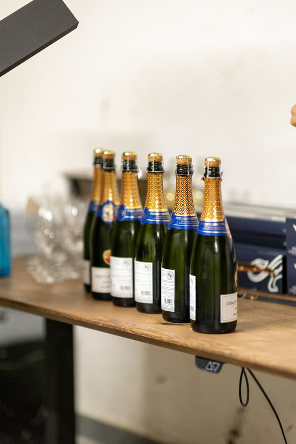 Flaskor med mousserande vin uppradade på en träbänk