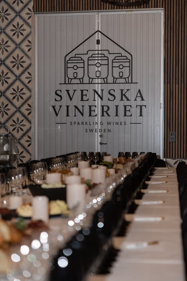 Svenska Vineriets lokal med ett långt dukat bord framför vinerilogotypen